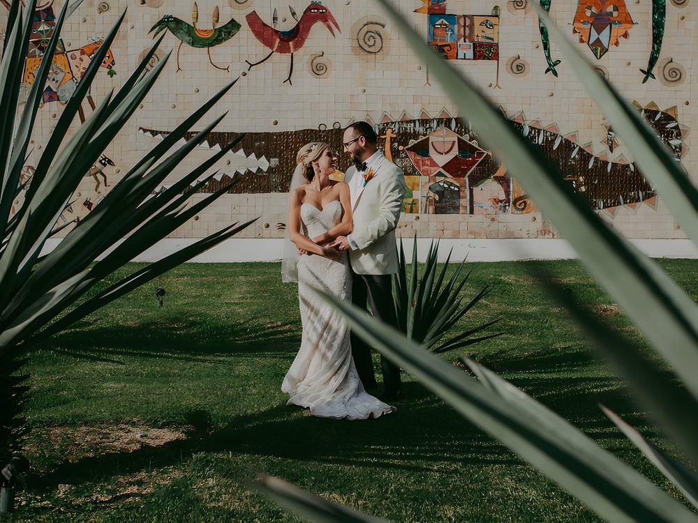 The bride and groom stand together on a lush green lawn, inspiring ideas for where to begin planning your wedding or destination wedding.