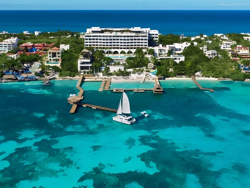 A catamaran sails near a hotel resort—an ideal spot for couples dreaming of a destination wedding or seeking inspiration as they start planning their special day.