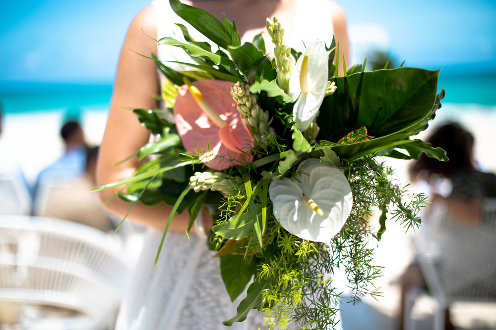 A person holding a vibrant tropical bouquet at an outdoor wedding—perfect inspiration for destination wedding unity ceremony ideas.