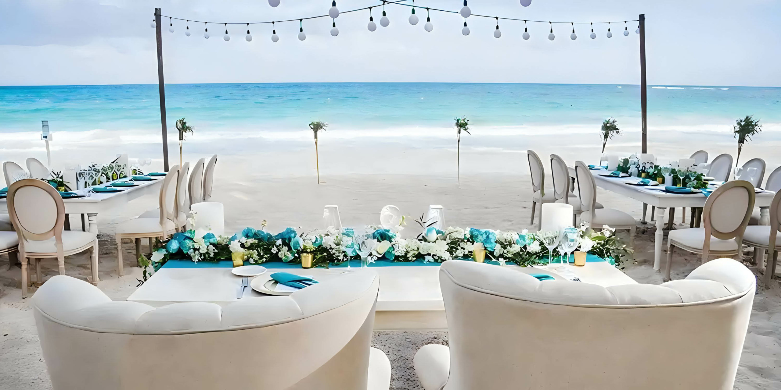 A beach wedding set up with white tables and chairs at Catalonia Grand Costa Mujeres.