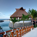 Thatched-roof pavilion by the water, an ideal setting for destination weddings in the Riviera Maya.