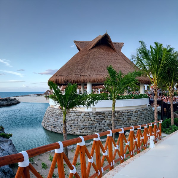 Thatched-roof pavilion by the water, an ideal setting for destination weddings in the Riviera Maya.