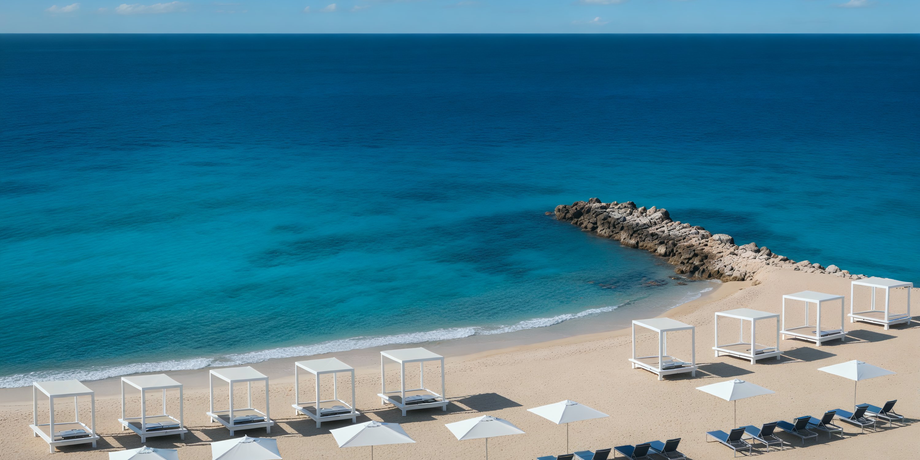 White cabanas and umbrellas adorned the sandy beach, creating a picturesque setting for a destination wedding by the azure sea.