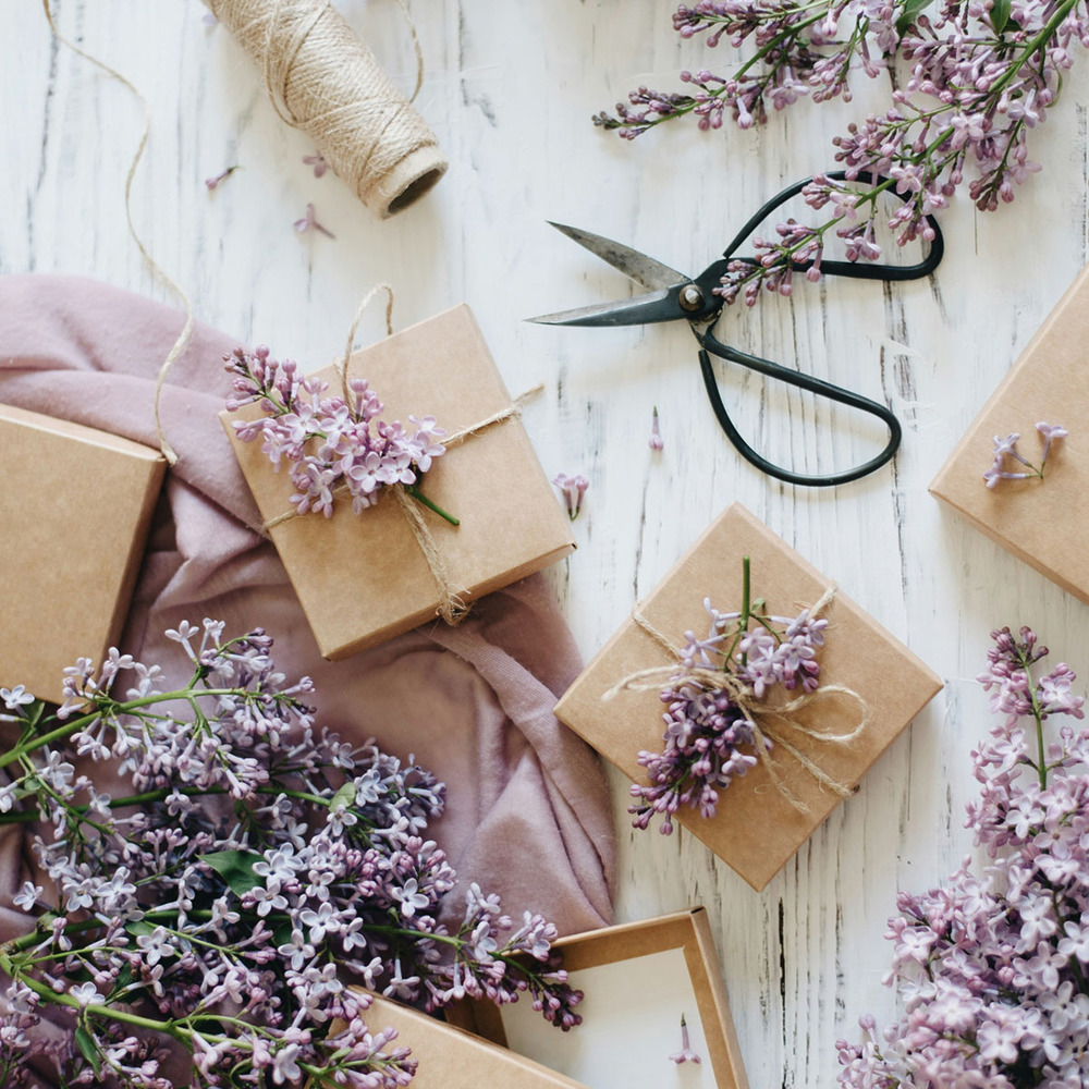 Lilac flowers wrapped in brown paper on a wooden table make the perfect birthday gift for a wife.