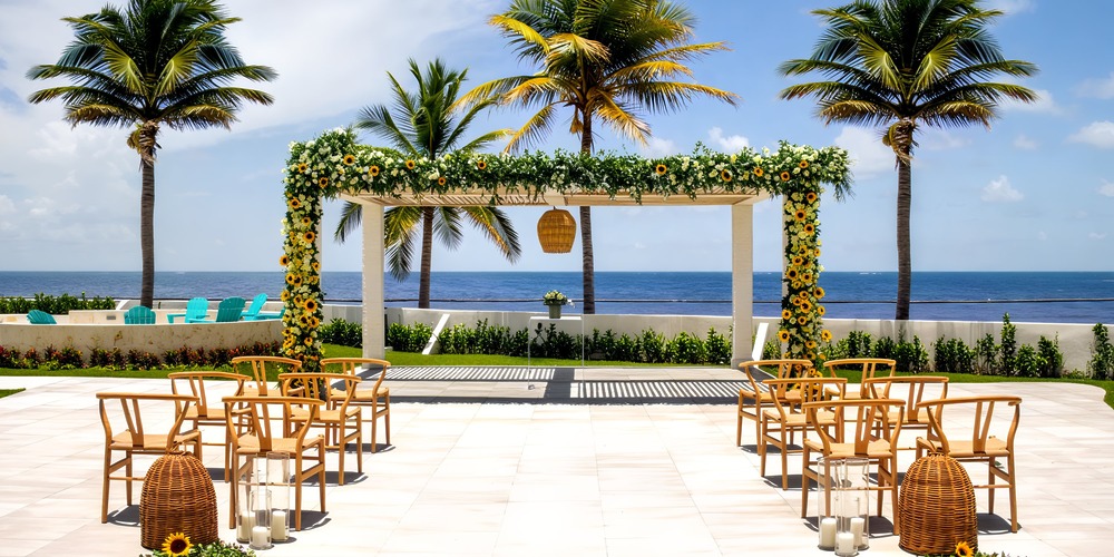 Destination wedding at Margaritaville Island Reserve Riviera Maya: a picturesque setup featuring chairs, a canopy, and stunning palm trees.