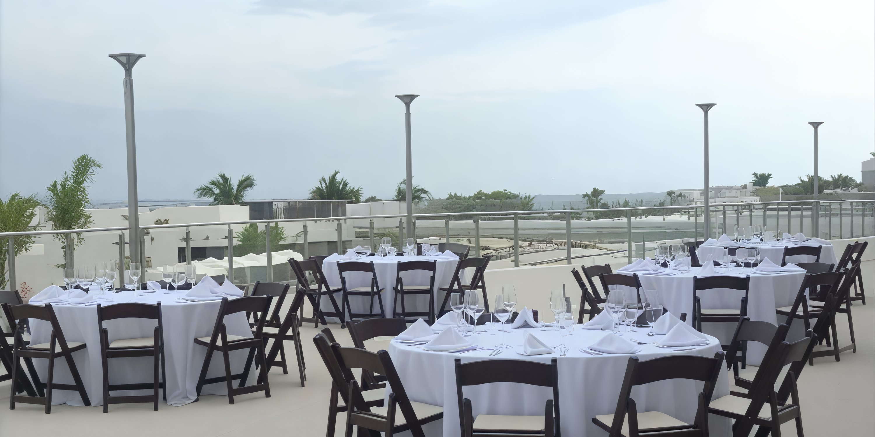 AVA Resort Cancun is the perfect venue for a destination wedding, featuring a charming patio adorned with round tables draped in white tablecloths and complemented by elegant wooden chairs.
