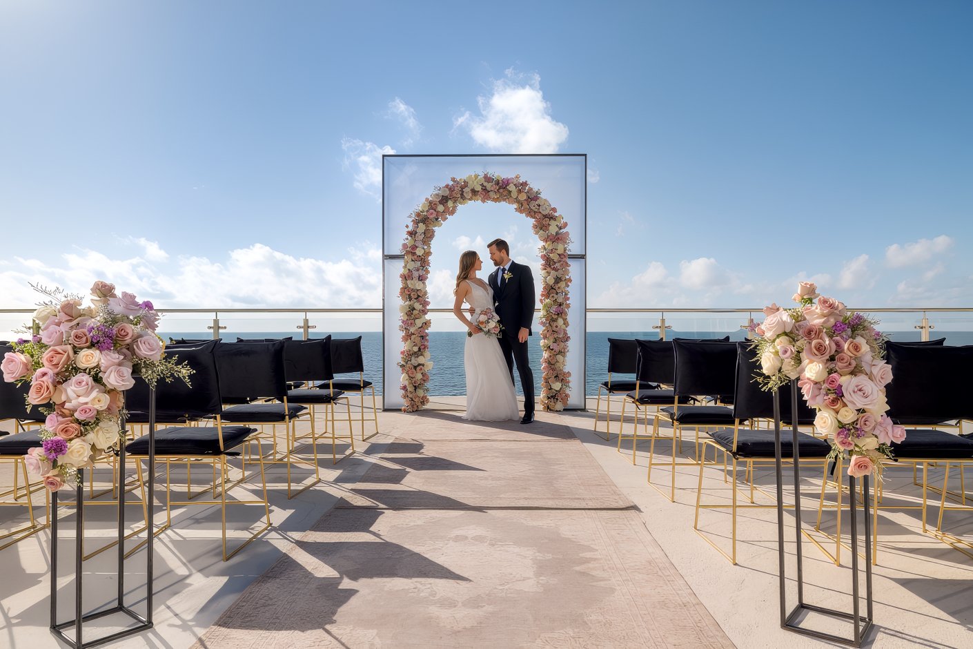 The bride and groom pose beneath a beautifully adorned floral arch at their destination wedding at AVA Resort Cancun.