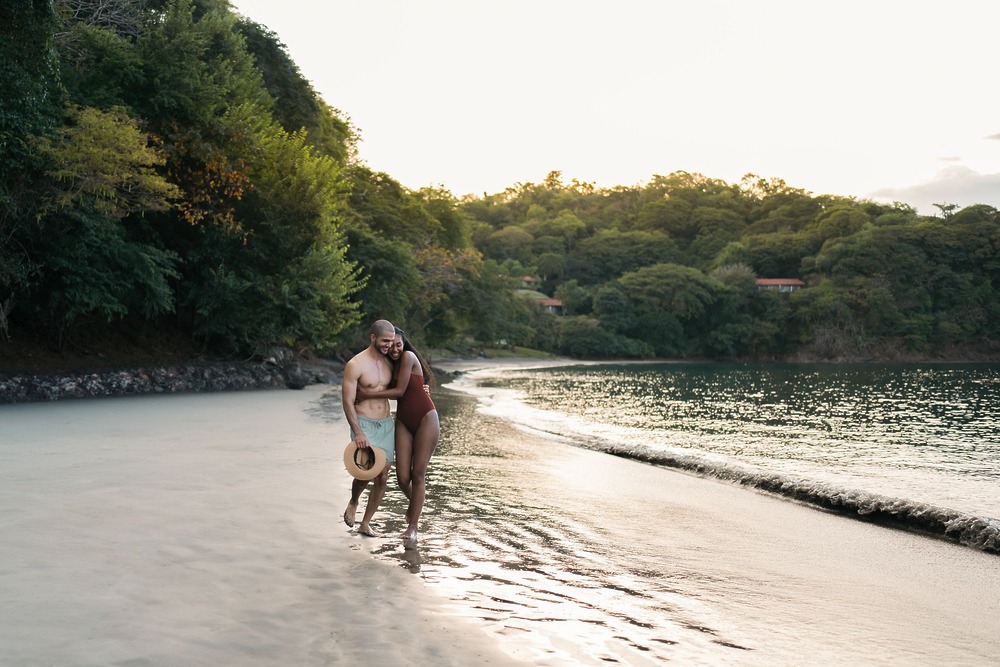 A couple strolls hand in hand along a sandy beach, an idyllic setting for a romantic Costa Rica destination wedding.