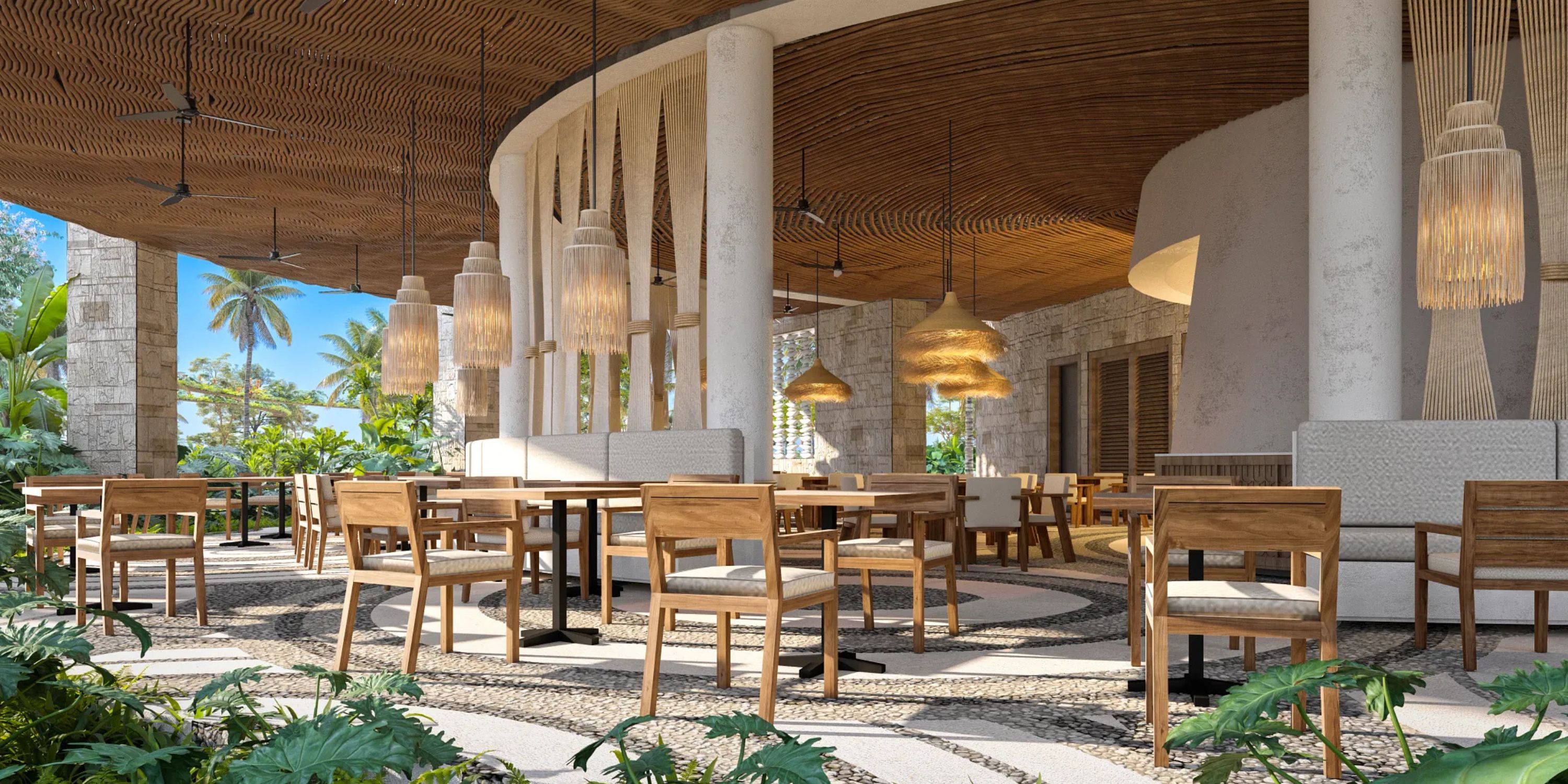 Experience open-air dining at Secrets Playa Blanca Costa Mujeres, surrounded by wooden tables, chairs, and lush tropical plants—an idyllic setting perfect for a romantic wedding reception or an unforgettable destination wedding celebration.