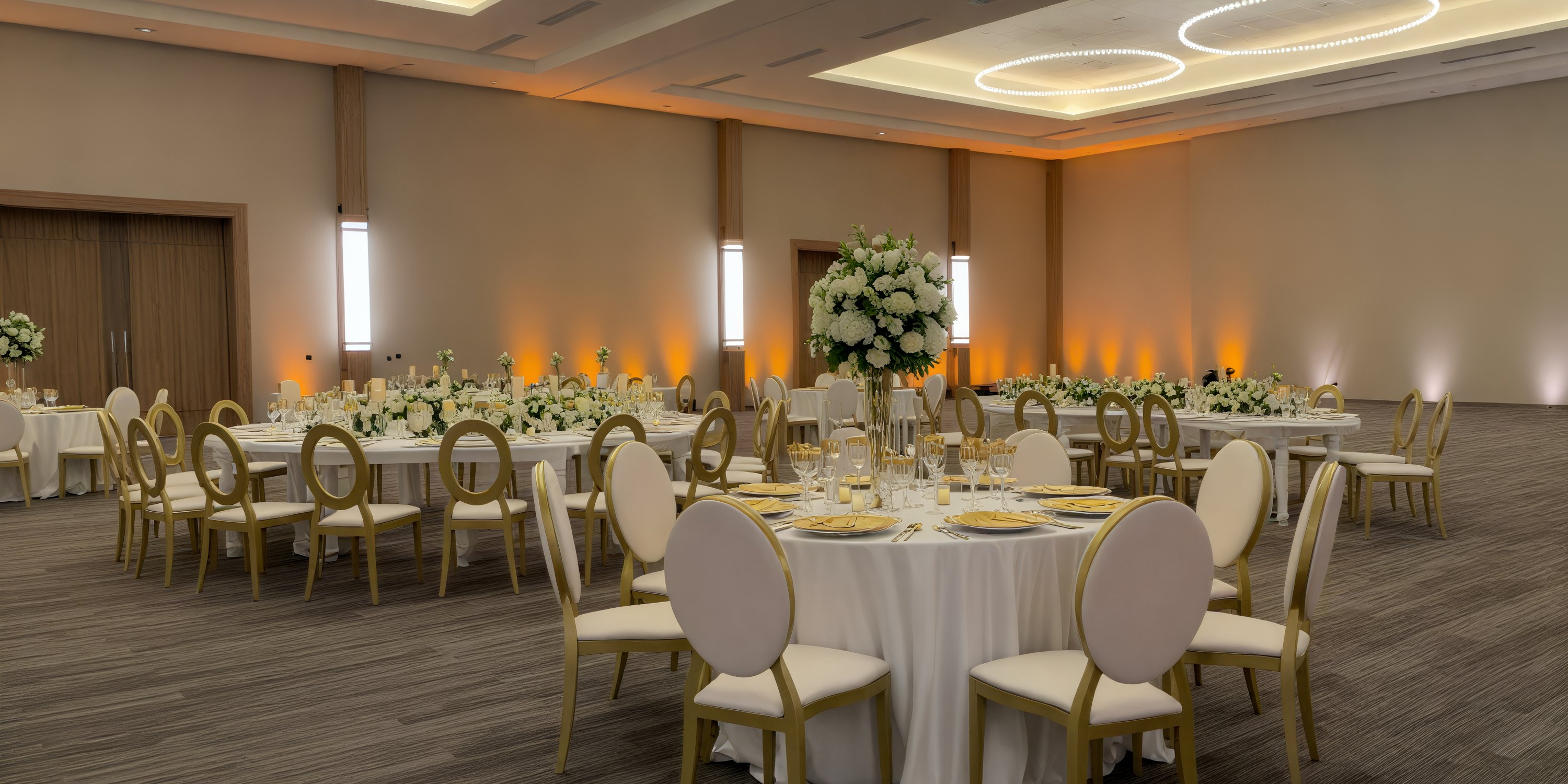 Secrets Tides banquet hall elegantly arranged for a destination wedding, featuring round tables adorned with white floral decor.