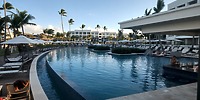 Secrets Tides offers a stunning resort pool, perfect for a destination wedding, with palm trees and lounges.