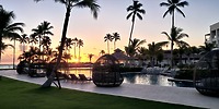 Secrets Tides resort poolside at sunset, perfect for a destination wedding, with lounge chairs and palms.