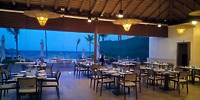 Secrets Tides: Open-air dining perfect for a destination wedding, set tables, wicker chairs, dusk beach view.
