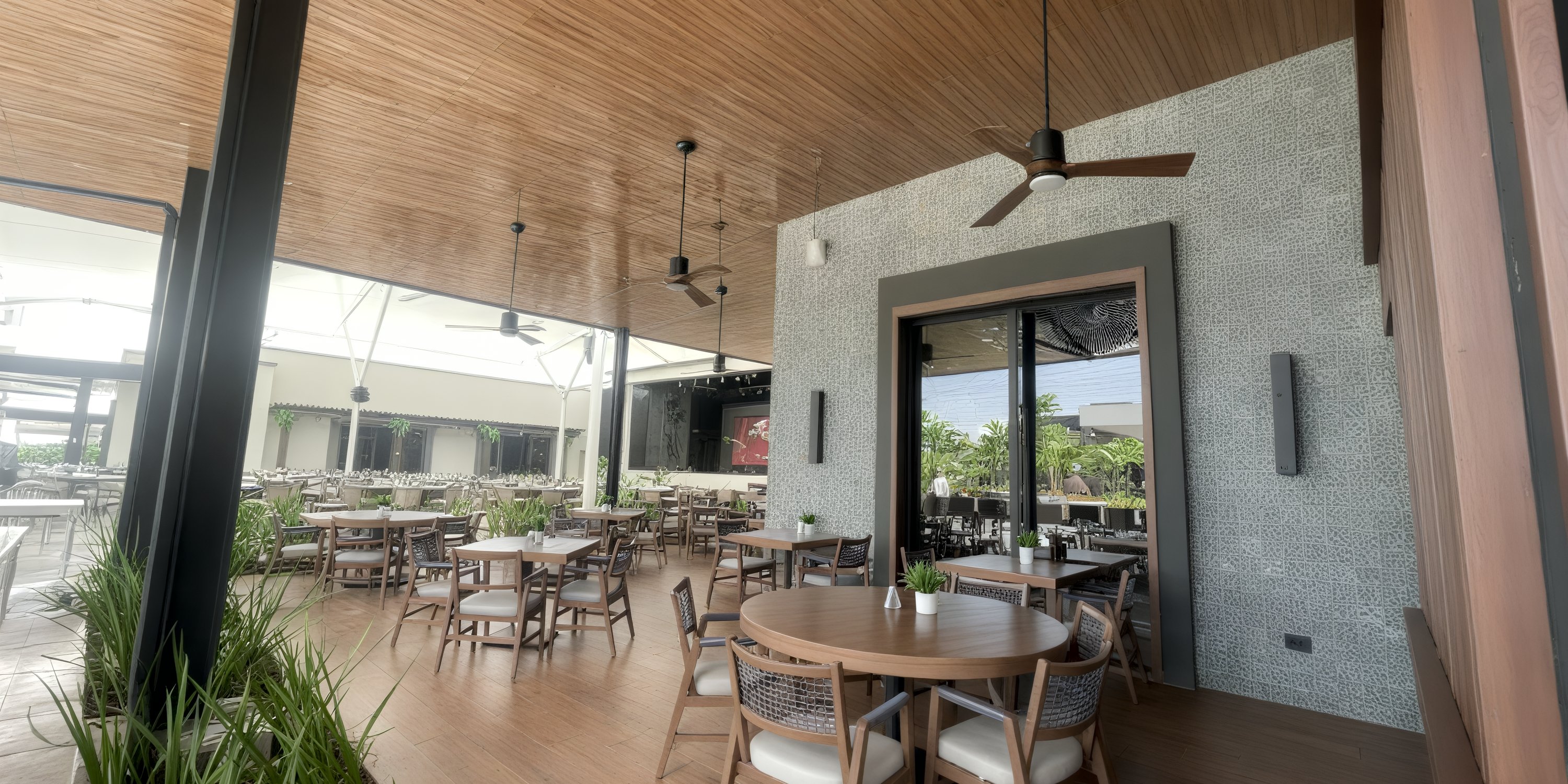 Secrets Tides: Modern open-air restaurant ideal for destination weddings, featuring wood tables, fans, greenery.