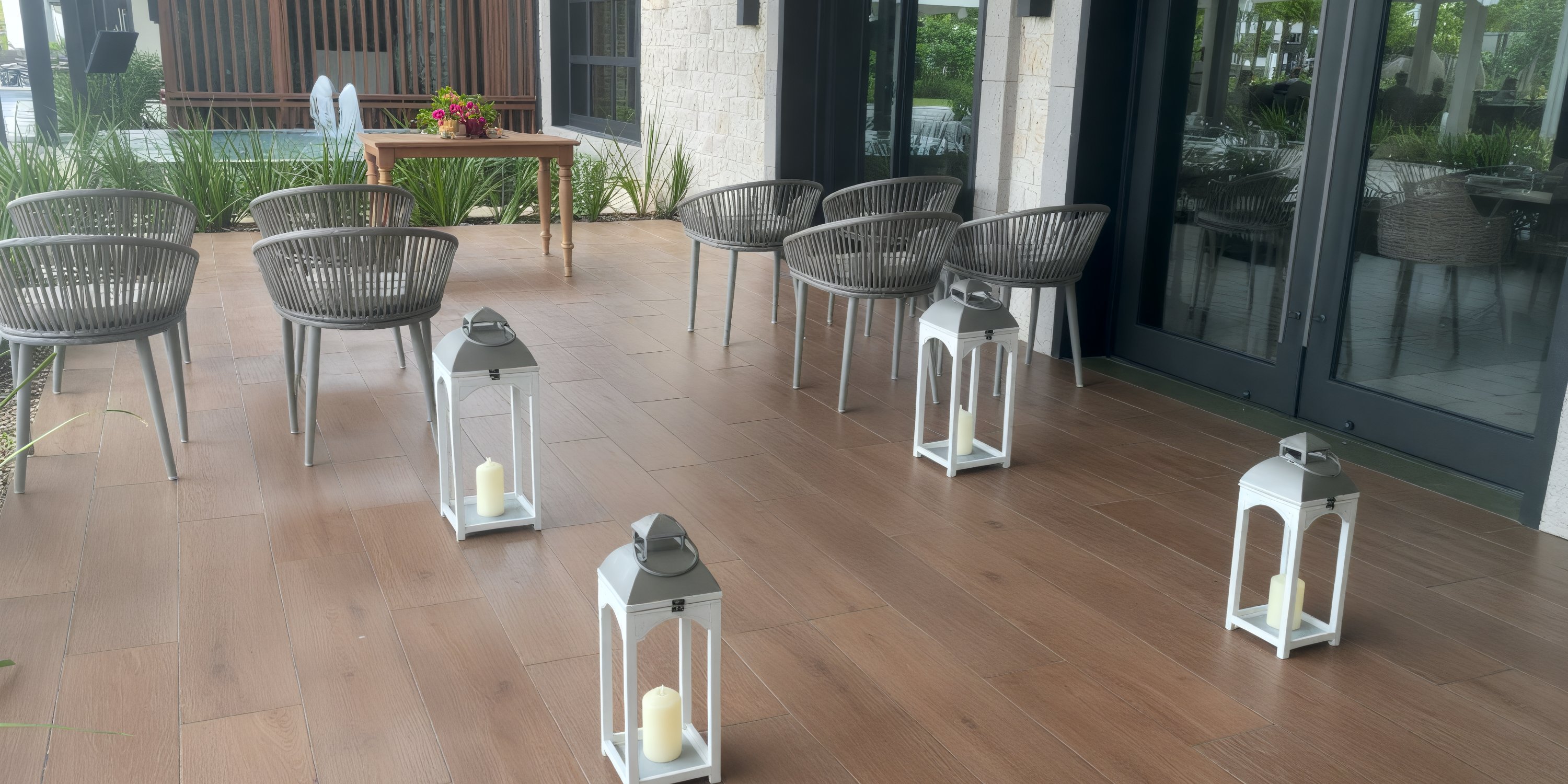 Lanterns with candles line a tiled patio set with chairs and a wooden table for a destination wedding.