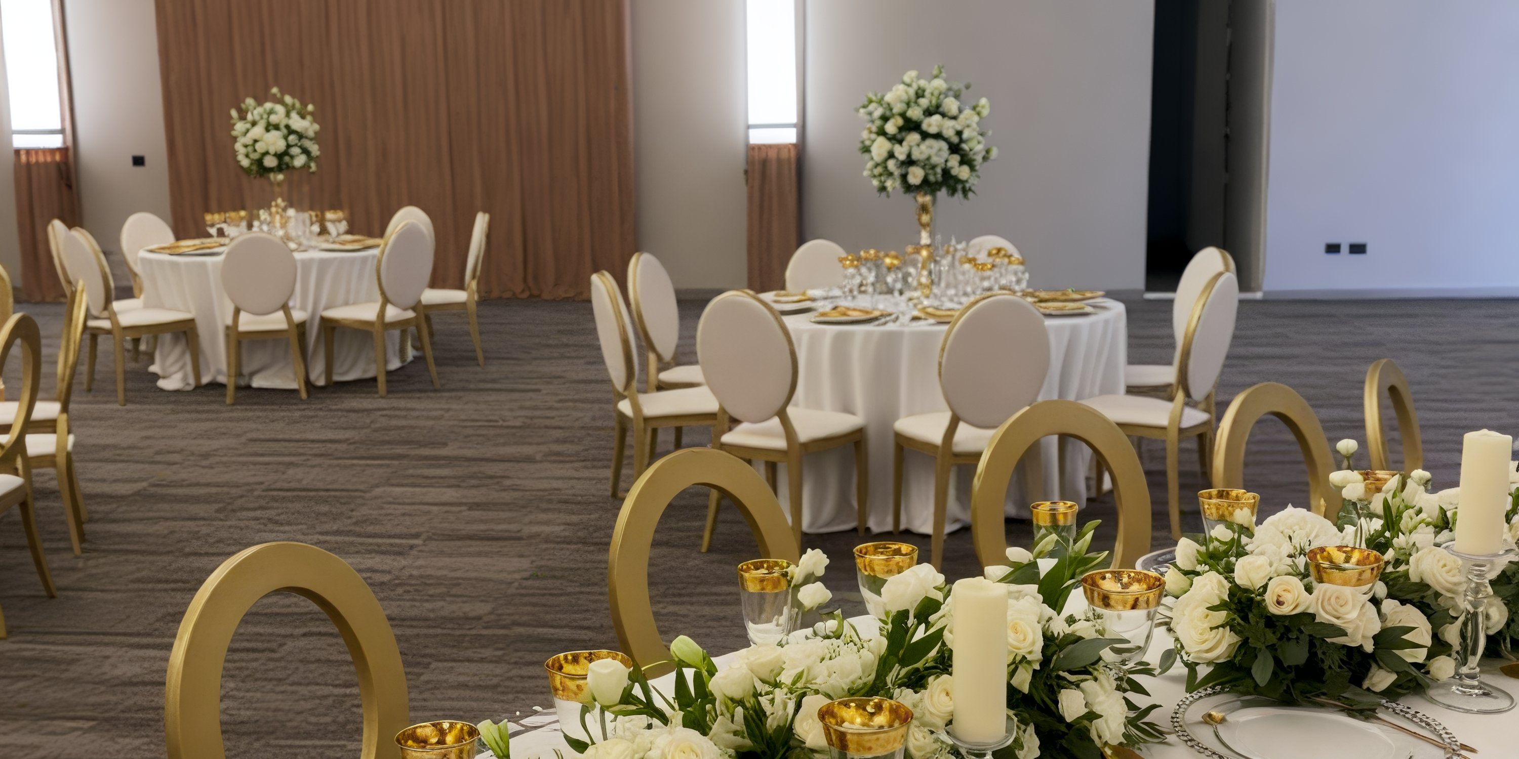 Secrets Tides banquet hall set for a destination wedding with round tables, white chairs, and gold accents.