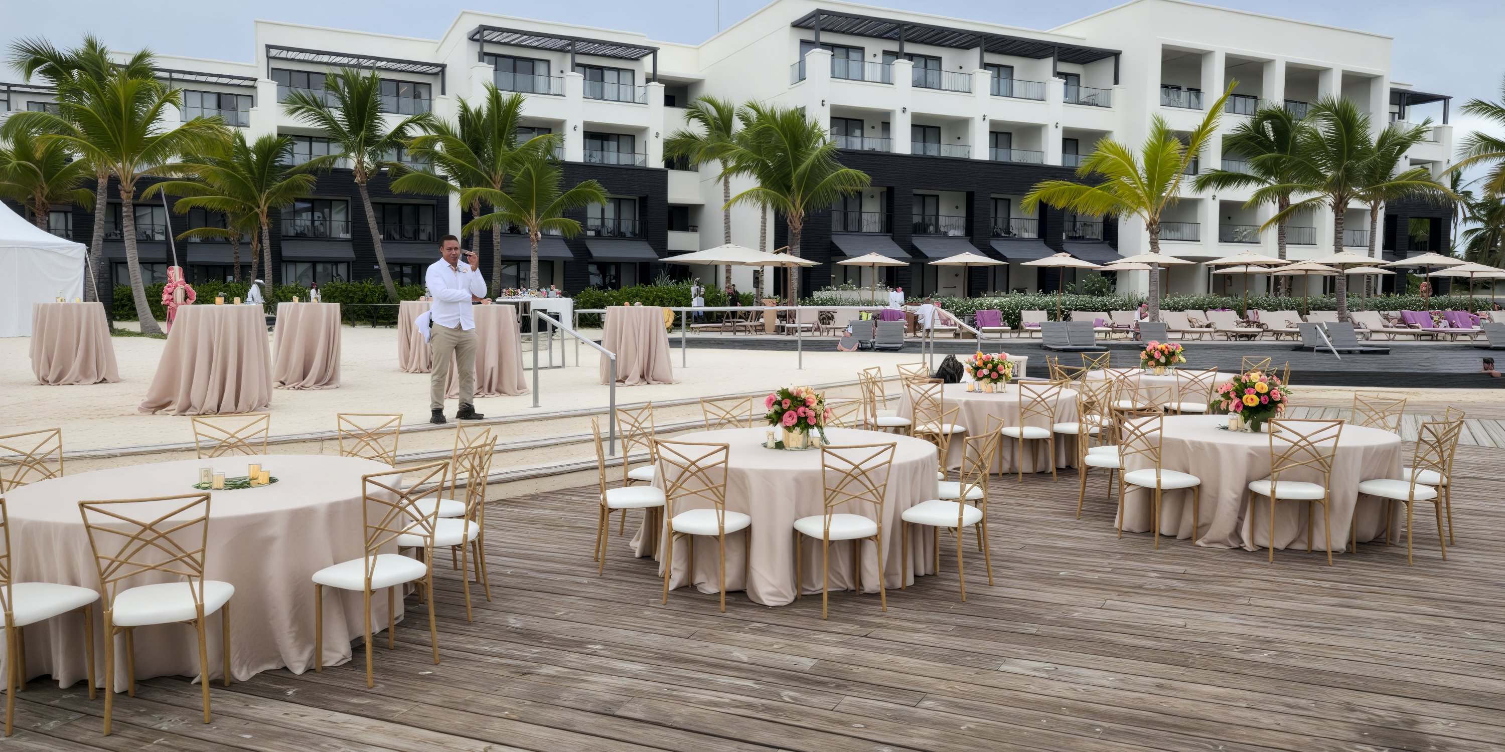 Destination wedding setup with round tables, chairs, and flowers outside Secrets Tides hotel.