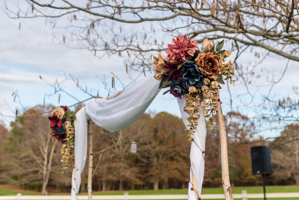 Elevate your destination wedding with an elegant outdoor arch adorned in white draping and faux blooms—an ideal choice for unforgettable wedding decor.