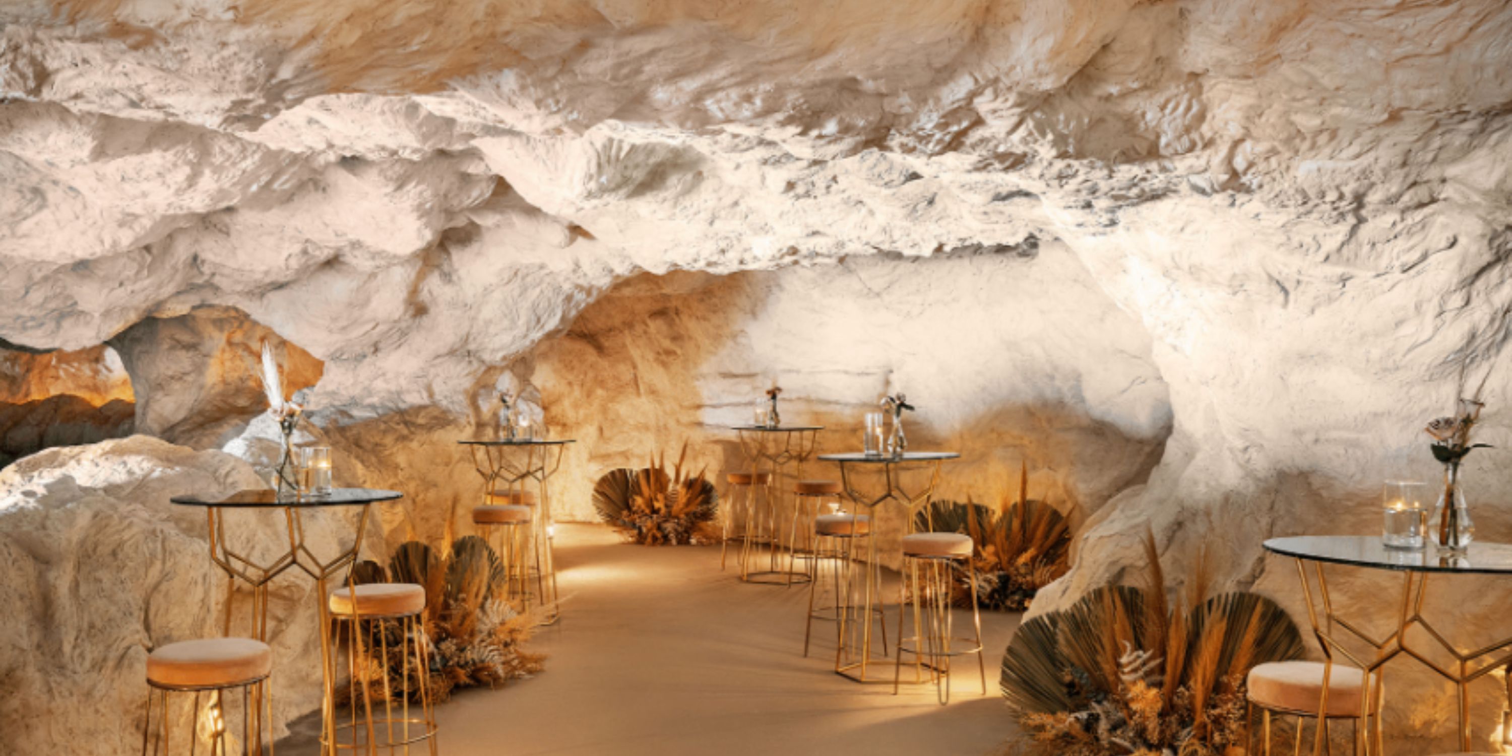 Cave-themed destination wedding room at Dreams Estrella del Mar Mazatlan with glass tables and florals.