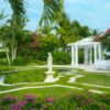 The garden at Sandals South Coast is transformed into a tropical paradise with its charming gazebo, winding pathways, elegant statues, palm trees, and vibrant flowers.