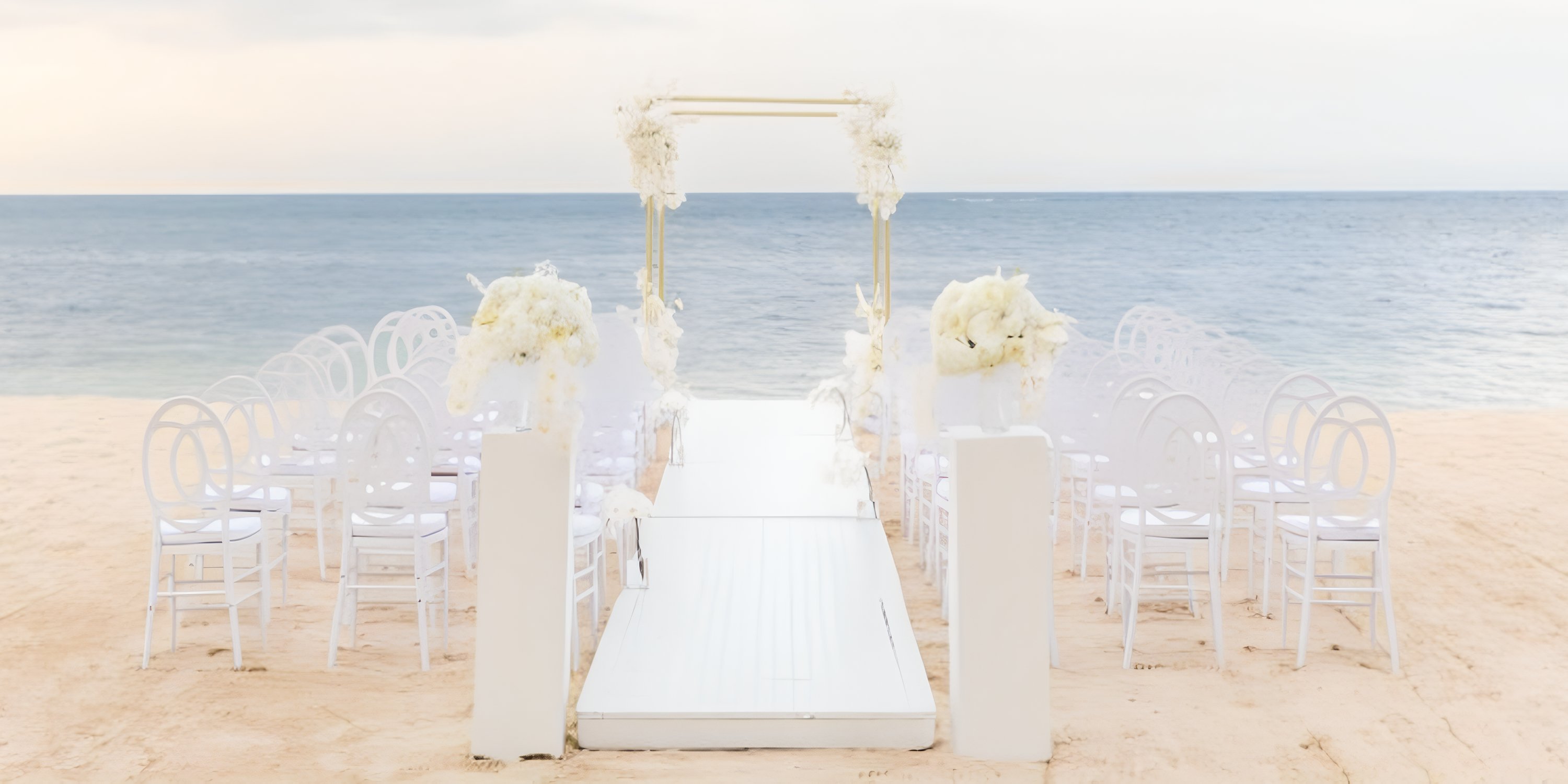 JOIA Rose Hall by Iberostar: destination wedding setup with white chairs facing the ocean.