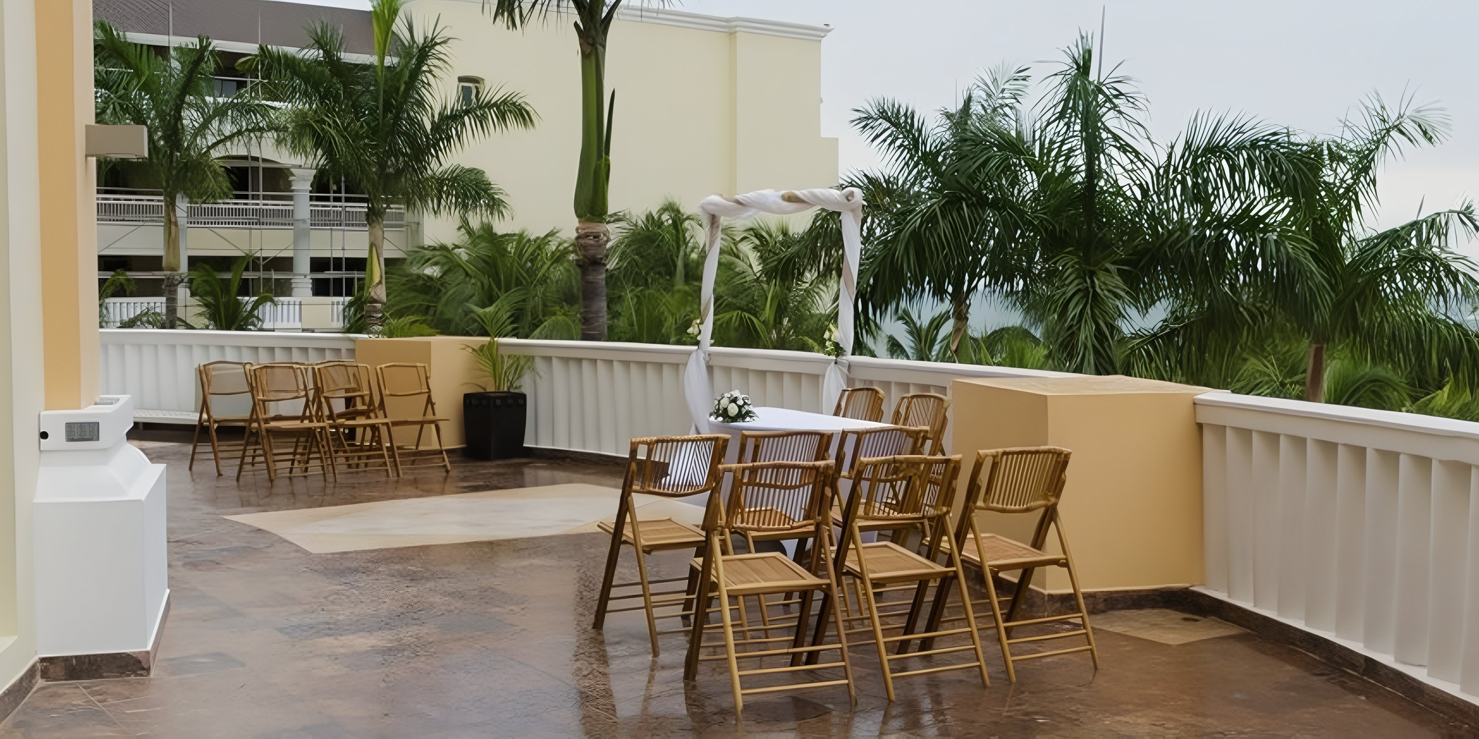 JOIA Rose Hall by Iberostar features a destination wedding terrace setup with wooden chairs and a floral arch.
