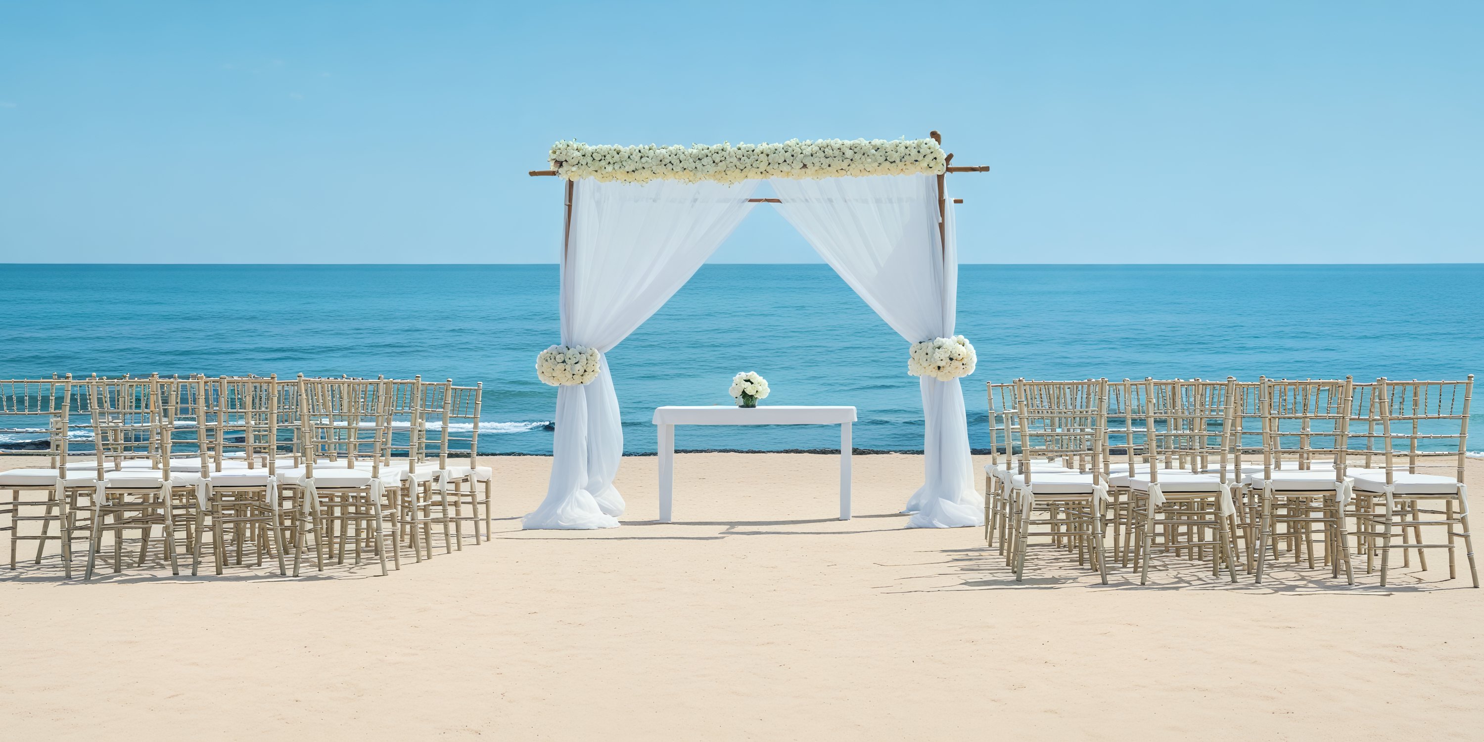 A destination wedding arrangement featuring chairs and a floral archway beautifully positioned to face the ocean.