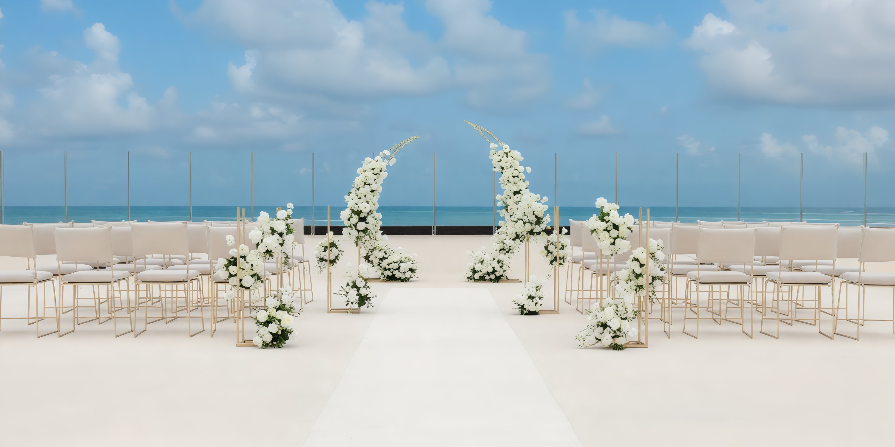 A destination wedding setup on the beach features white chairs and floral decorations, all perfectly arranged to face the ocean.