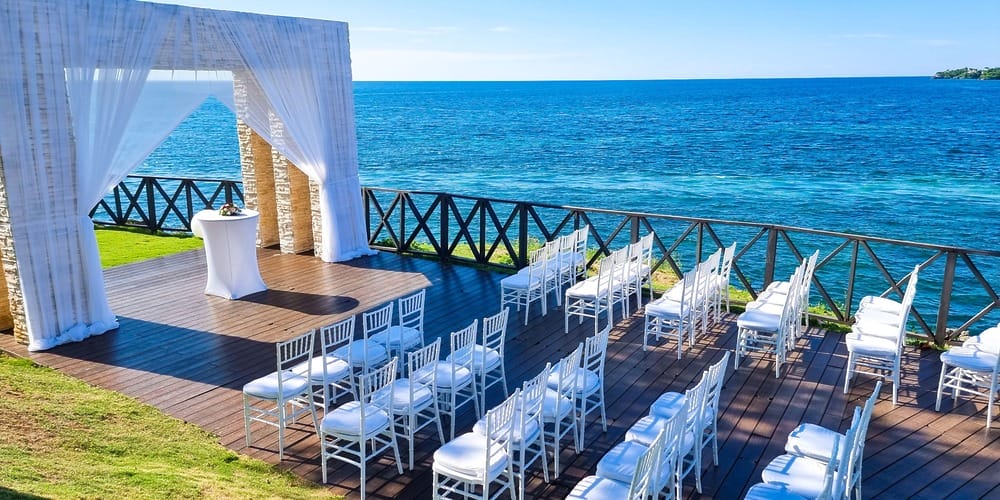 Jamaica destination wedding spot with ocean view, white chairs, arch; wedding packages under $3,000.