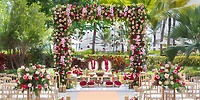 Destination wedding at Lopesan Costa Bavaro featuring a floral arch, vibrant blooms, and elegant seating.