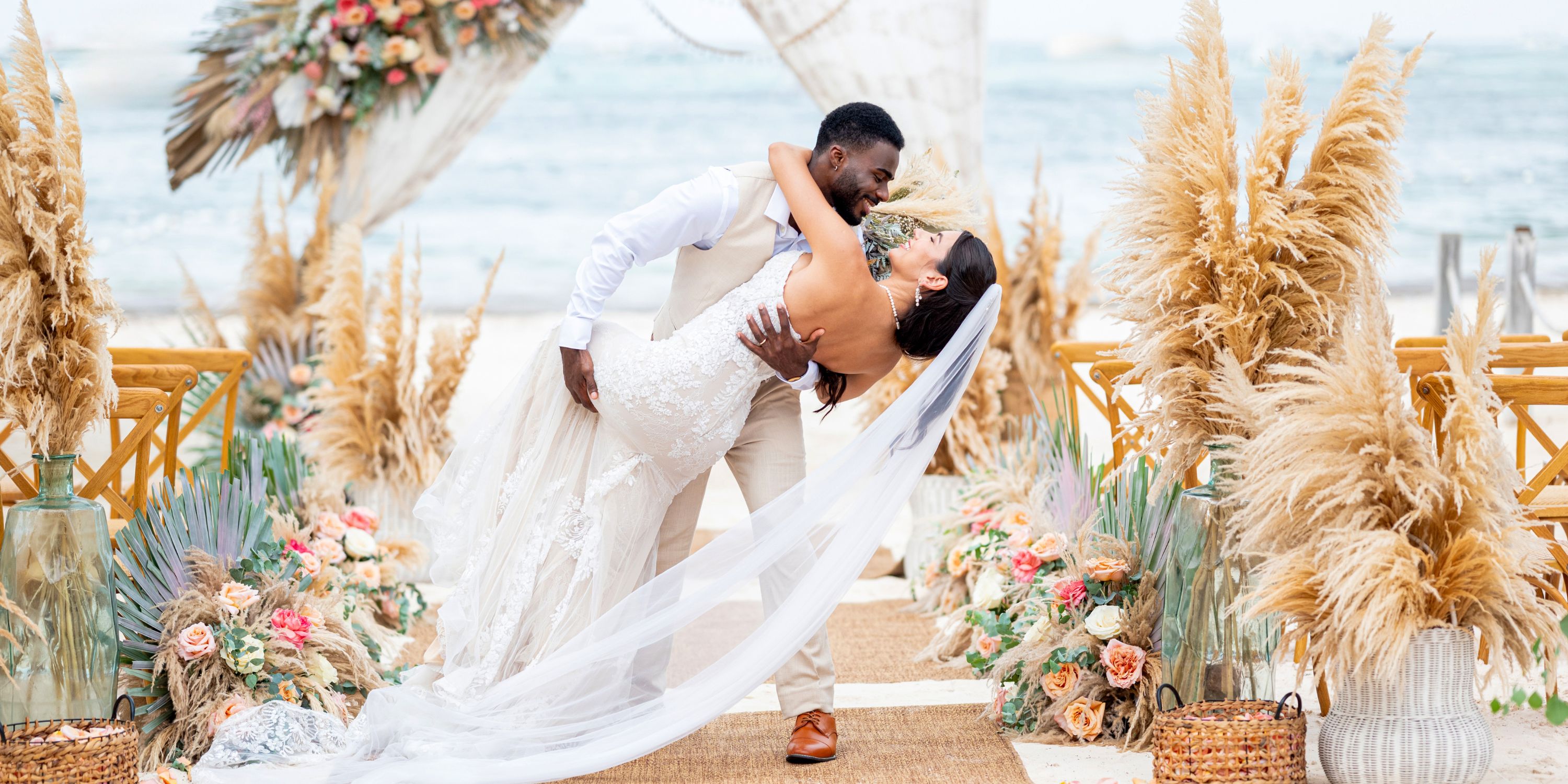 A groom kisses his bride at a romantic destination wedding at Lopesan Costa Bavaro with florals and pampas grass.