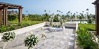 Destination wedding setup at Lopesan Costa Bavaro featuring white florals, clear chairs, and palm trees.