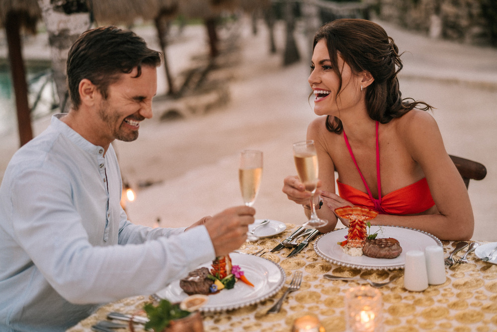 A man and woman raise their champagne glasses in a joyful toast, celebrating their affordable destination wedding package.