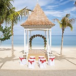 A beachside gazebo set up for a destination wedding in Jamaica, with decorated chairs and ocean views.