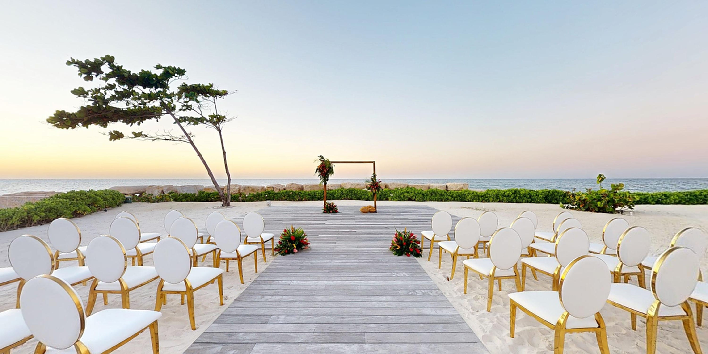 Rows of chairs face a wooden beach altar at a Princess Grand Jamaica destination wedding.