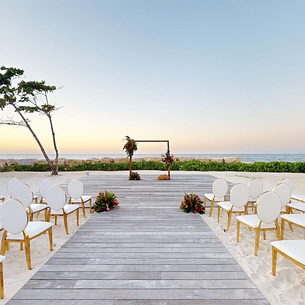 Destination wedding ceremony setup with rows of chairs facing an altar on a beach.