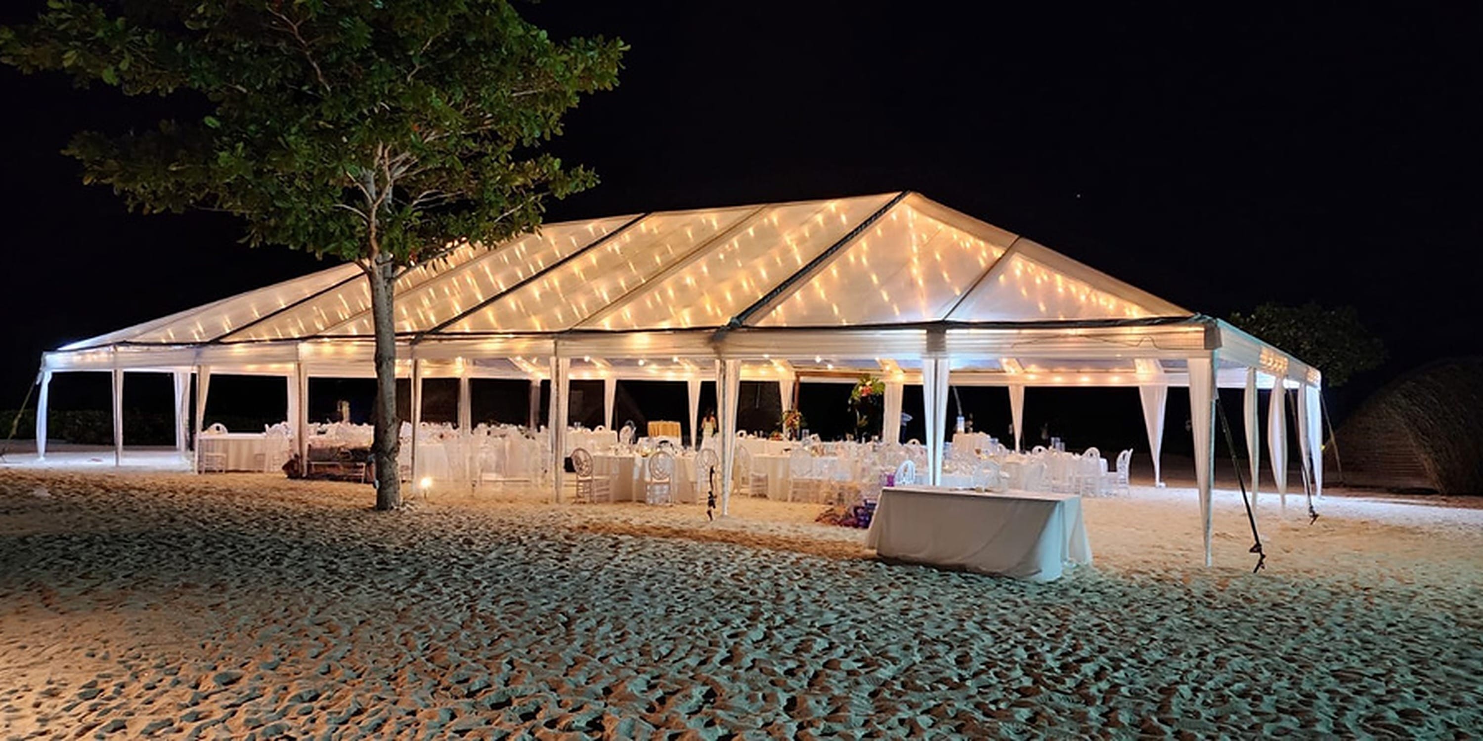 A large, illuminated destination wedding tent on the beach at Princess Grand Jamaica.