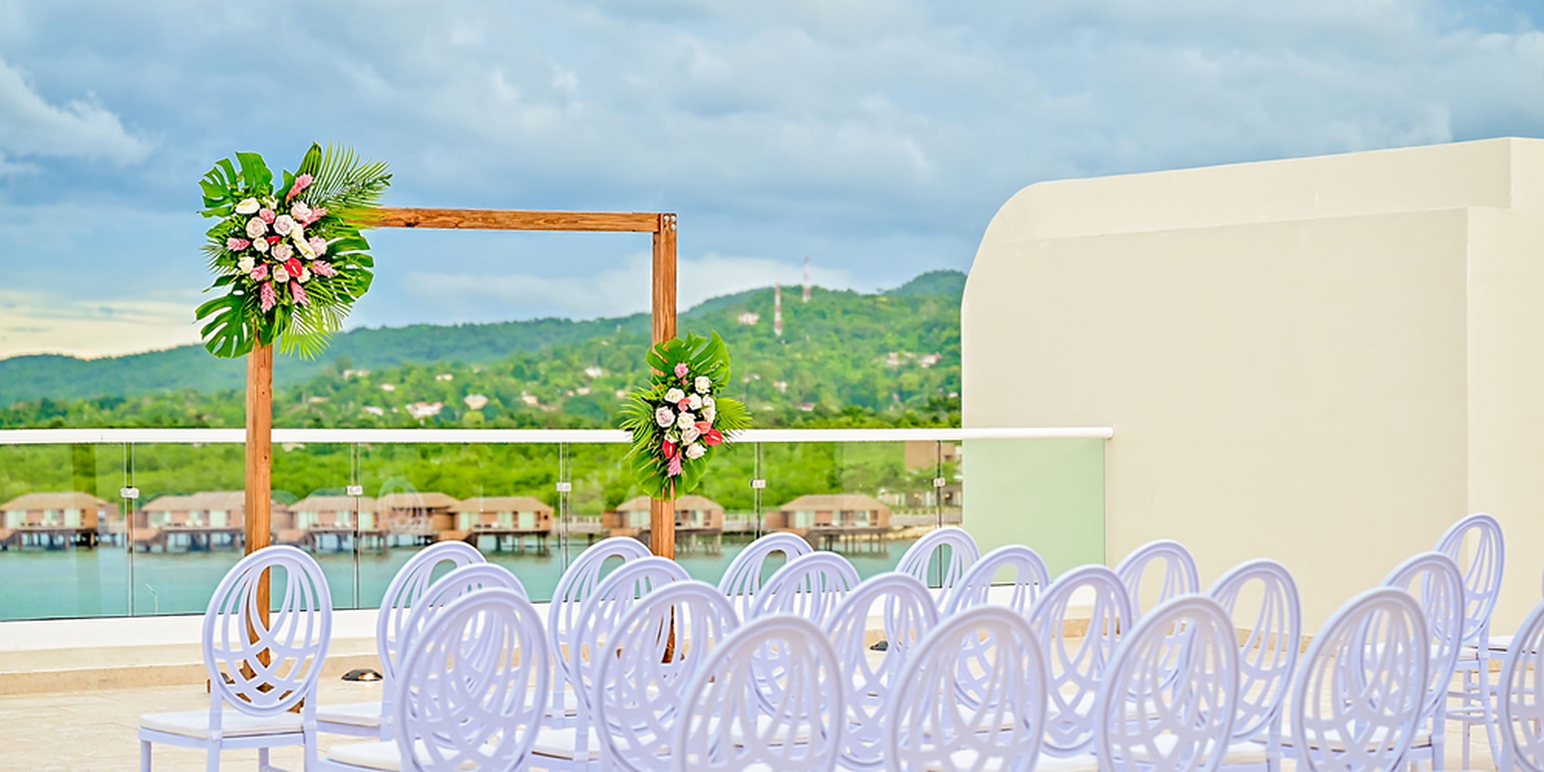 Rows of white chairs face a floral wooden arch for a destination wedding at Princess Grand Jamaica.