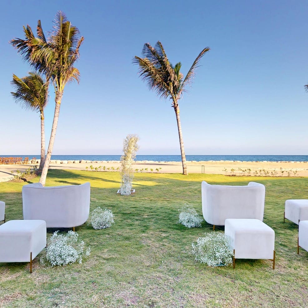 White lounge furniture on a seaside lawn for a destination wedding.