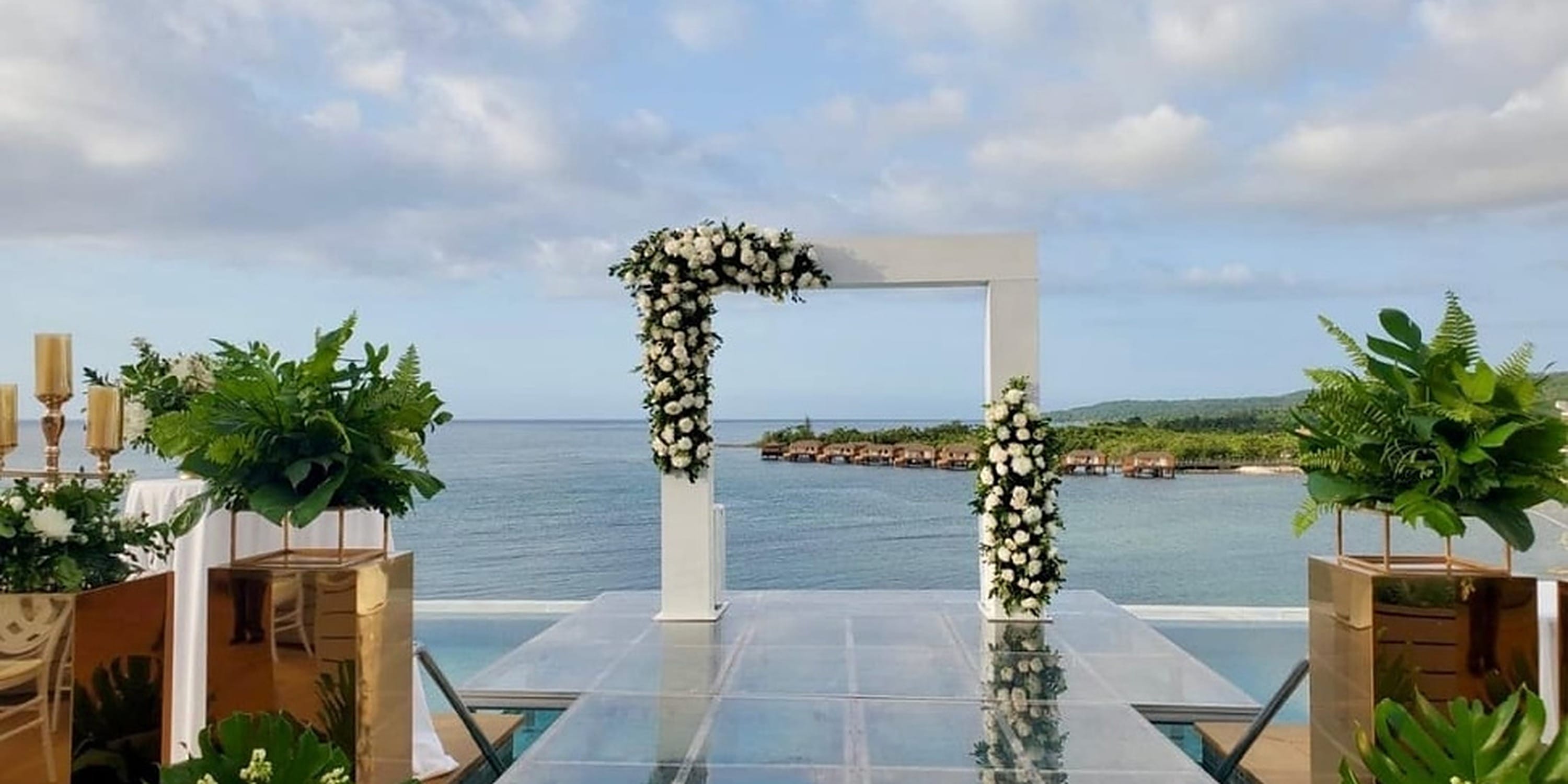 Flower-covered wedding arch on a glass platform overlooking the ocean at Princess Grand Jamaica.