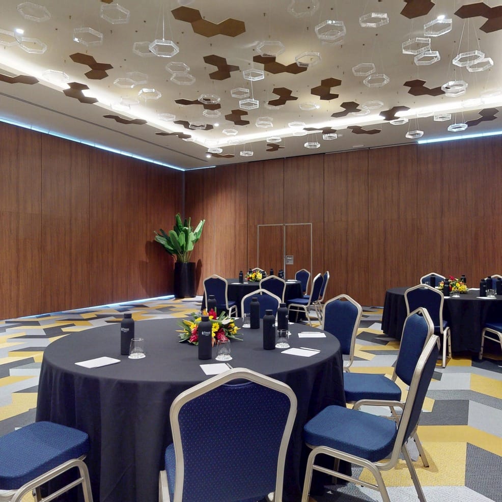 Round tables set for a wedding reception in a modern conference room.