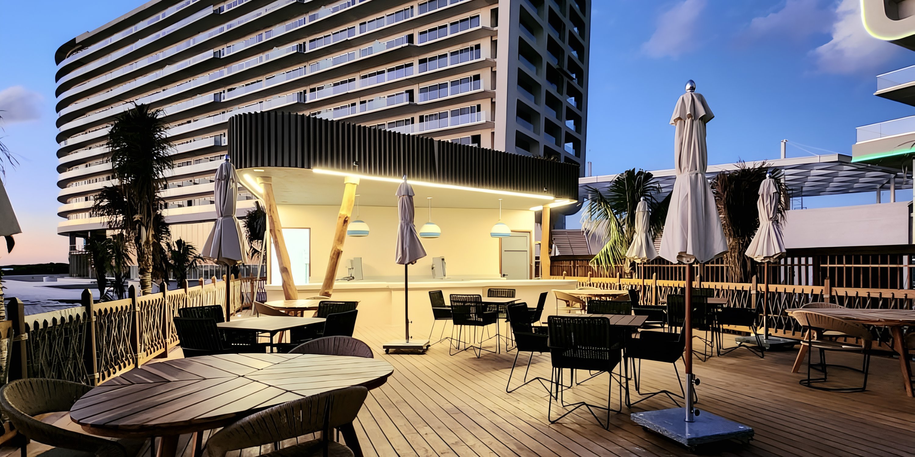 Outdoor seating with tables and chairs, perfect for a destination wedding, beside Hyatt Vivid Grand Island at dusk.