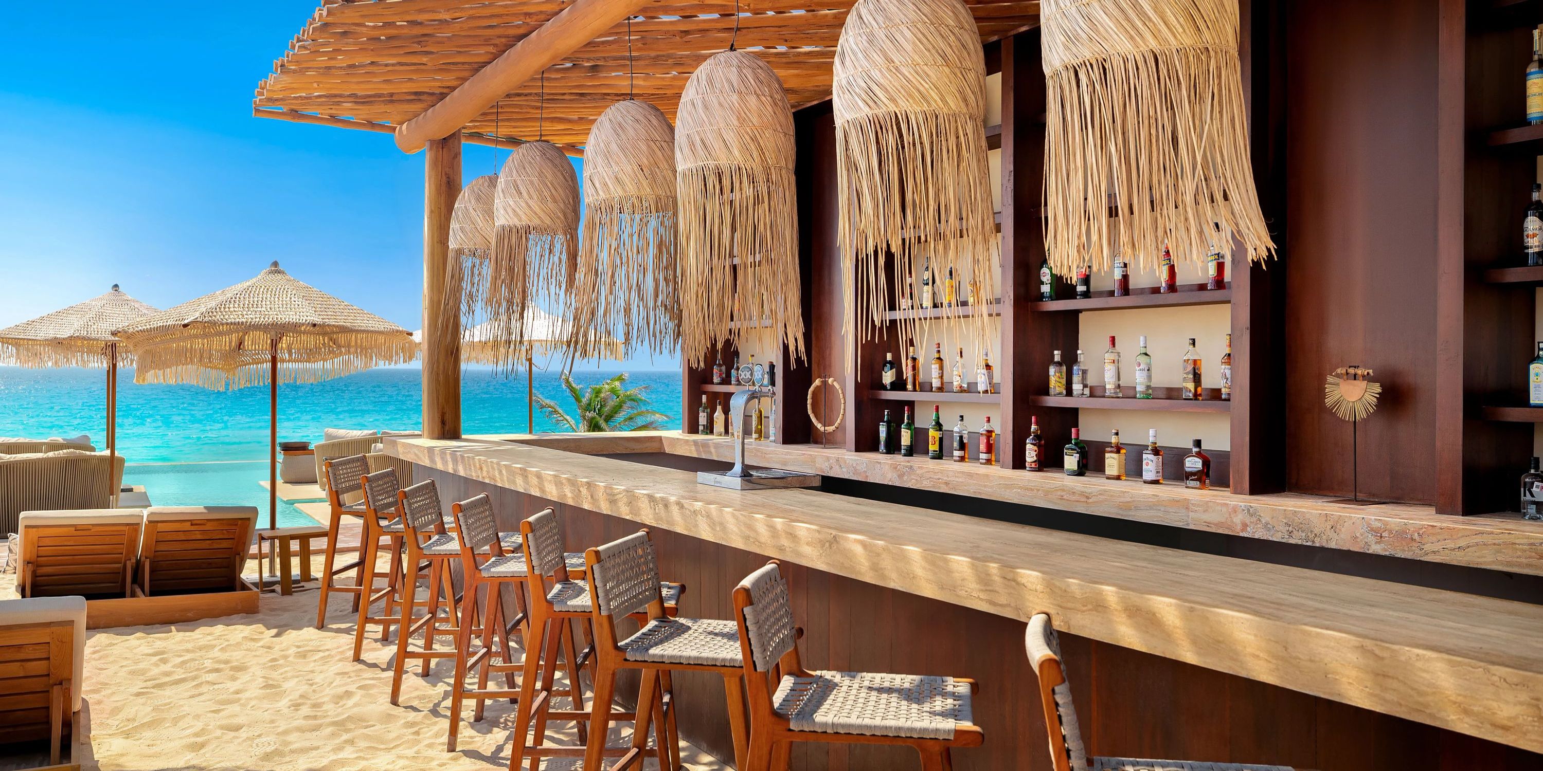 Hyatt Vivid Grand Island: A charming beach bar featuring a straw roof, wooden stools, and breathtaking ocean views—perfect for a memorable destination wedding backdrop.