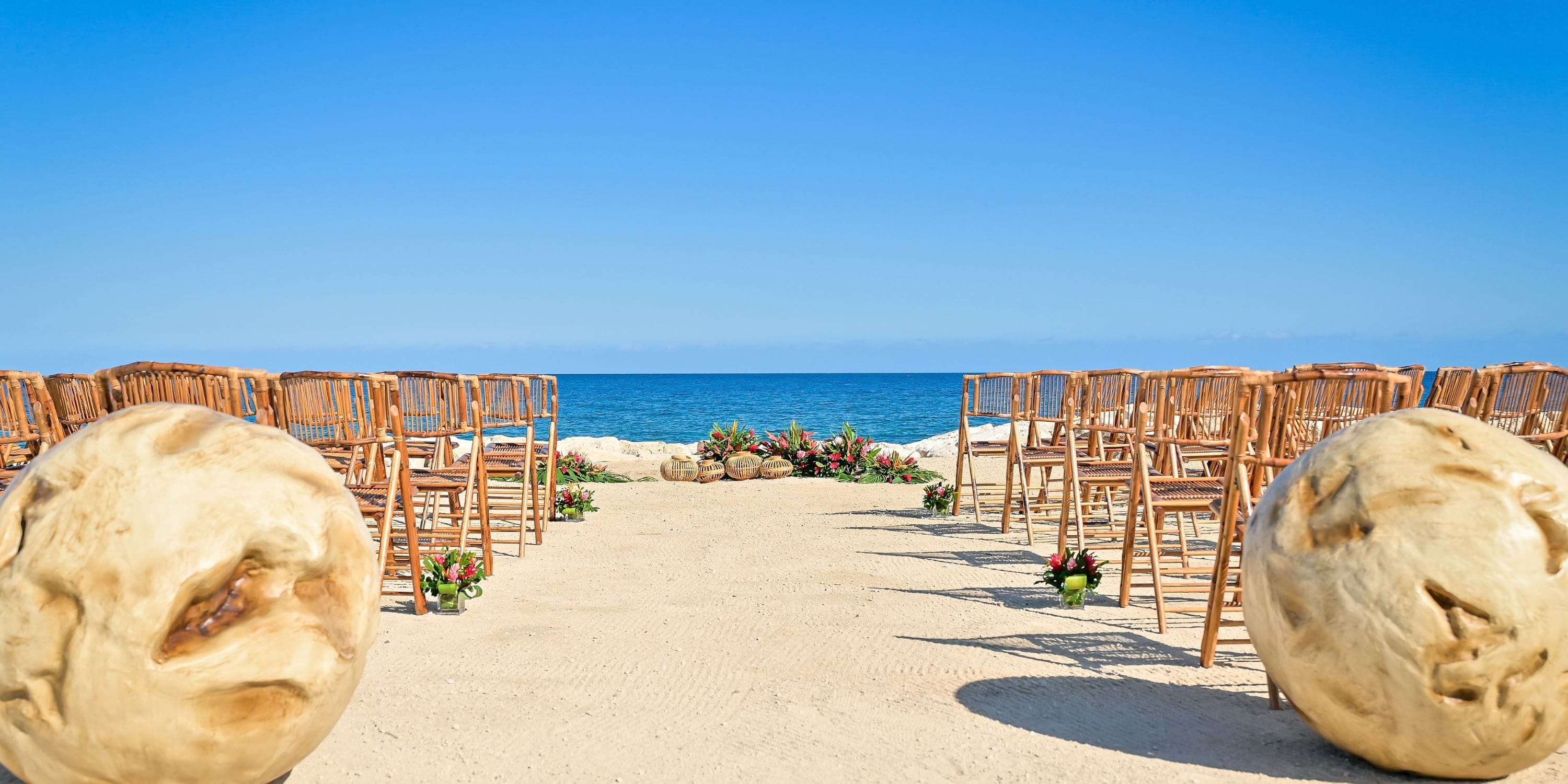 Wooden chairs at Princess Grand Jamaica face the ocean, set up for a destination wedding ceremony.