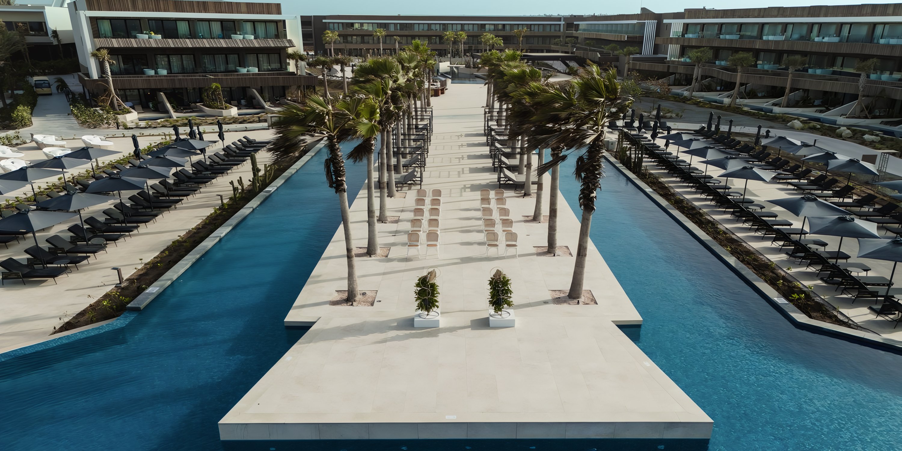 Stone walkway with palms between two pools at Secrets Baby Beach Aruba, perfect for a destination wedding.