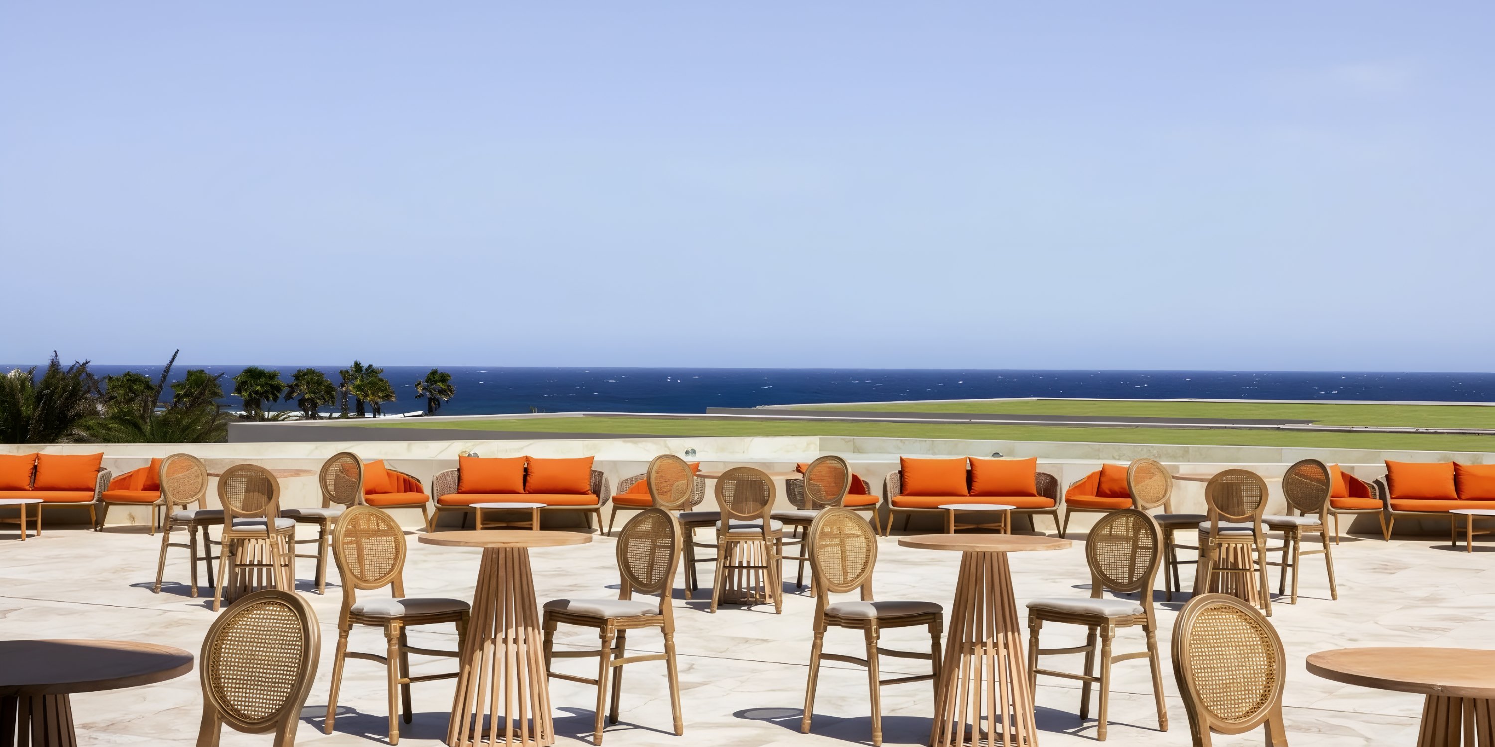 Secrets Baby Beach Aruba patio, perfect for a destination wedding, with wicker chairs, orange sofas, and ocean view.
