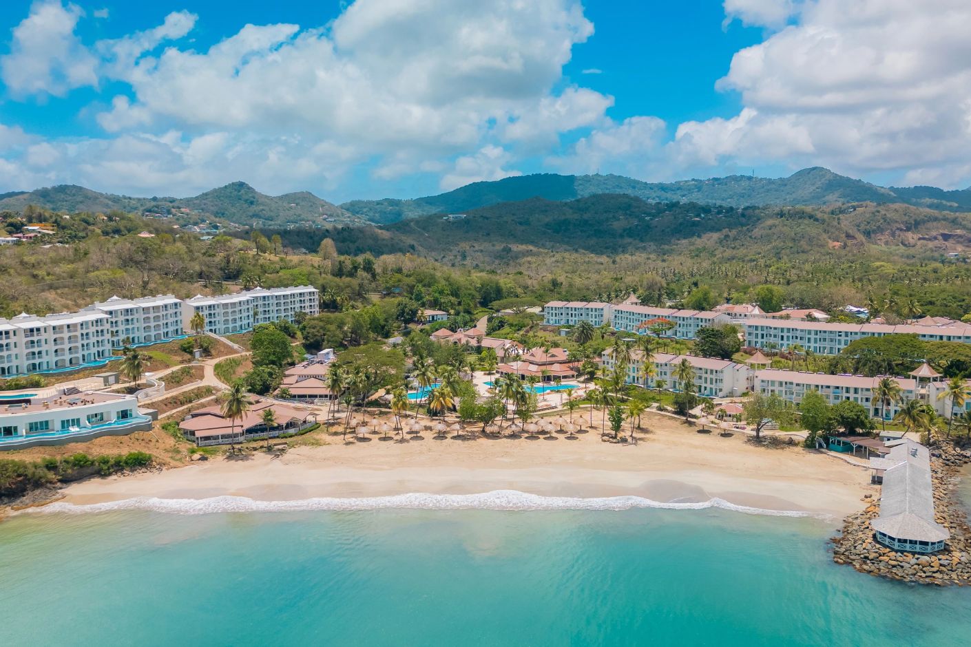 Aerial view of Secrets St Lucia resort, perfect for a destination wedding, with pools, palms, and mountains.