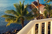 Balcony view at Secrets St Lucia: palm trees, rocky shore, and oceanfront destination wedding venue.