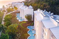 Aerial view of Secrets St Lucia, a stylish wedding destination with white buildings, pools, and gardens.