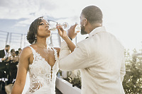 Carina and Marvin in formal attire toast with wine glasses at their outdoor destination wedding.